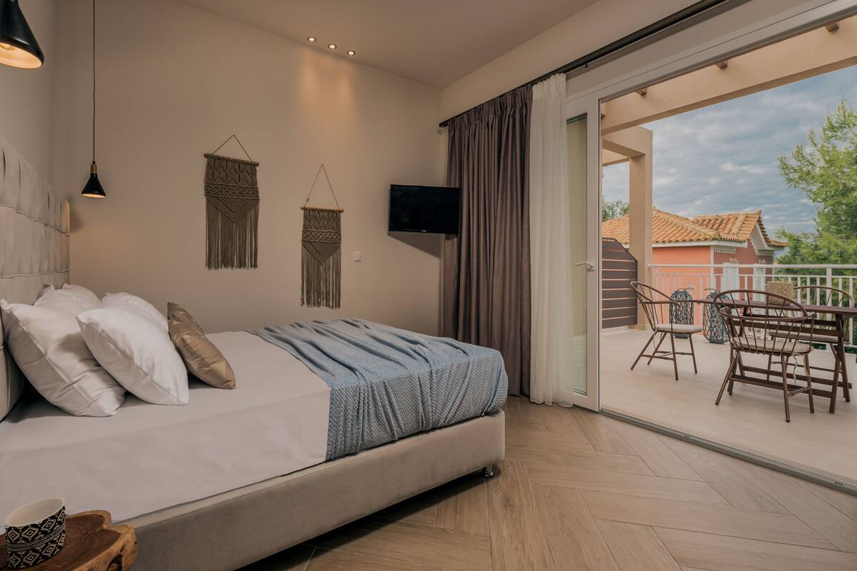 Una camera da letto con un letto, una televisione e un balcone con mobili da esterno.