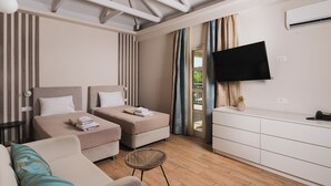 Ein modernes Hotelzimmer mit zwei Betten, einer Couch, einem Fernseher und einem kleinen Tisch.