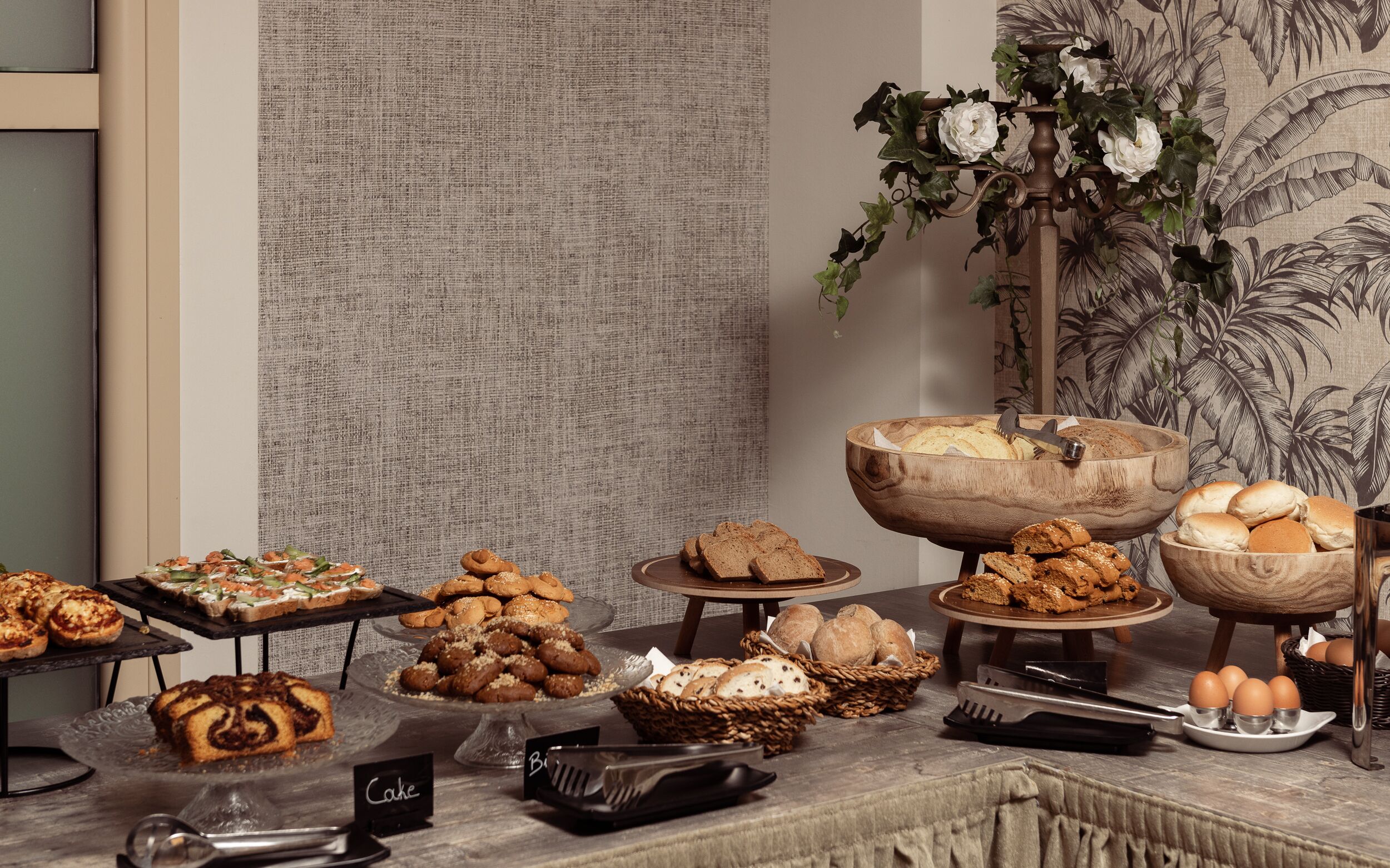 A buffet table with various baked goods, a cake station, and a fruit bowl.