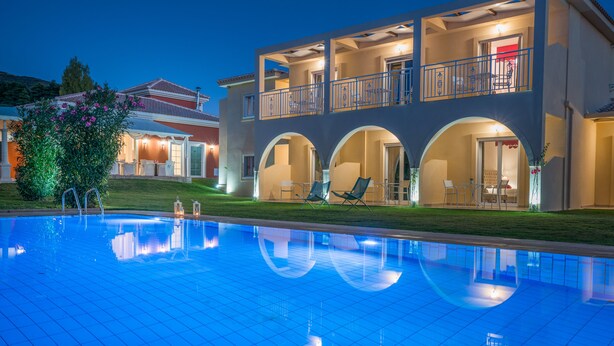 Ein zweistöckiges Gebäude mit Schwimmbad, Außenbereich zum Sitzen und einem gut beleuchteten Balkon.