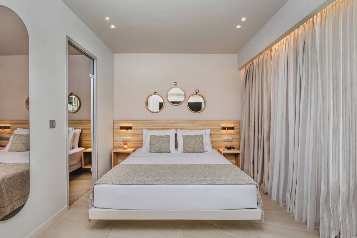 A modern bedroom with a large bed, bedside tables, and a mirror.