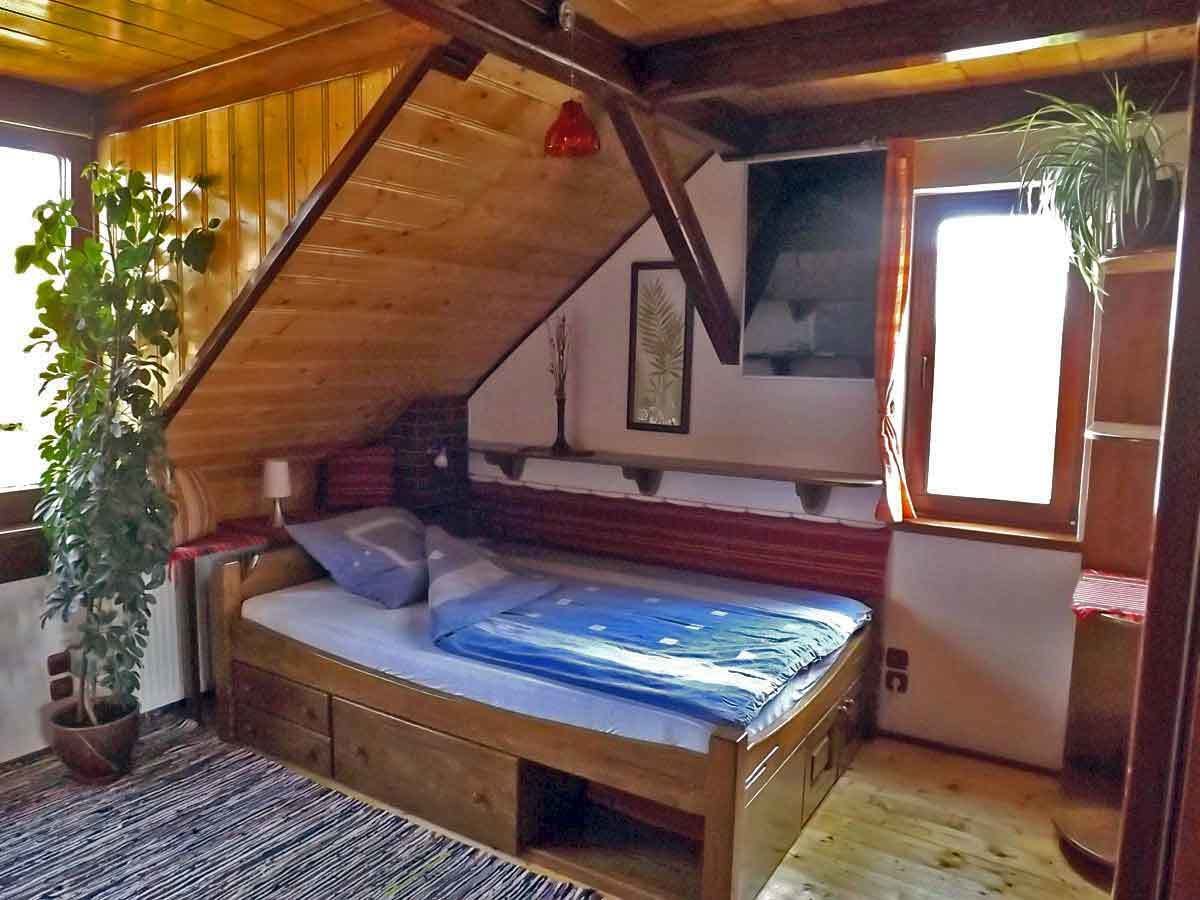 Une pièce chaleureuse, aménagée comme un chalet en bois, avec un lit, une fenêtre et une plante en pot.