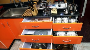 Een keuken met oranje kastjes, een spoelbak en diverse kookgerei.