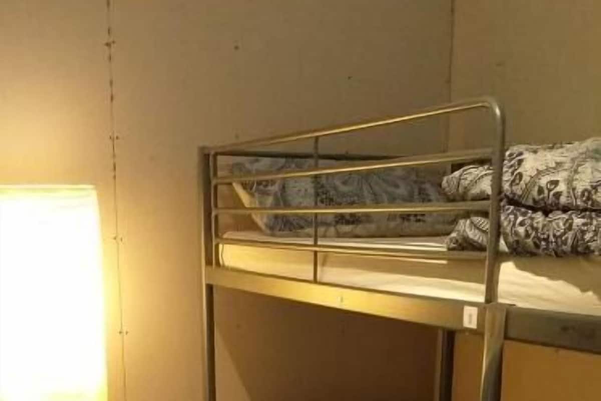 A bunk bed room with a blue floor, a lamp, and a power outlet on the wall.