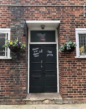Enter the Queens Hostel through the welcoming entrance, flanked by blooming flower baskets.