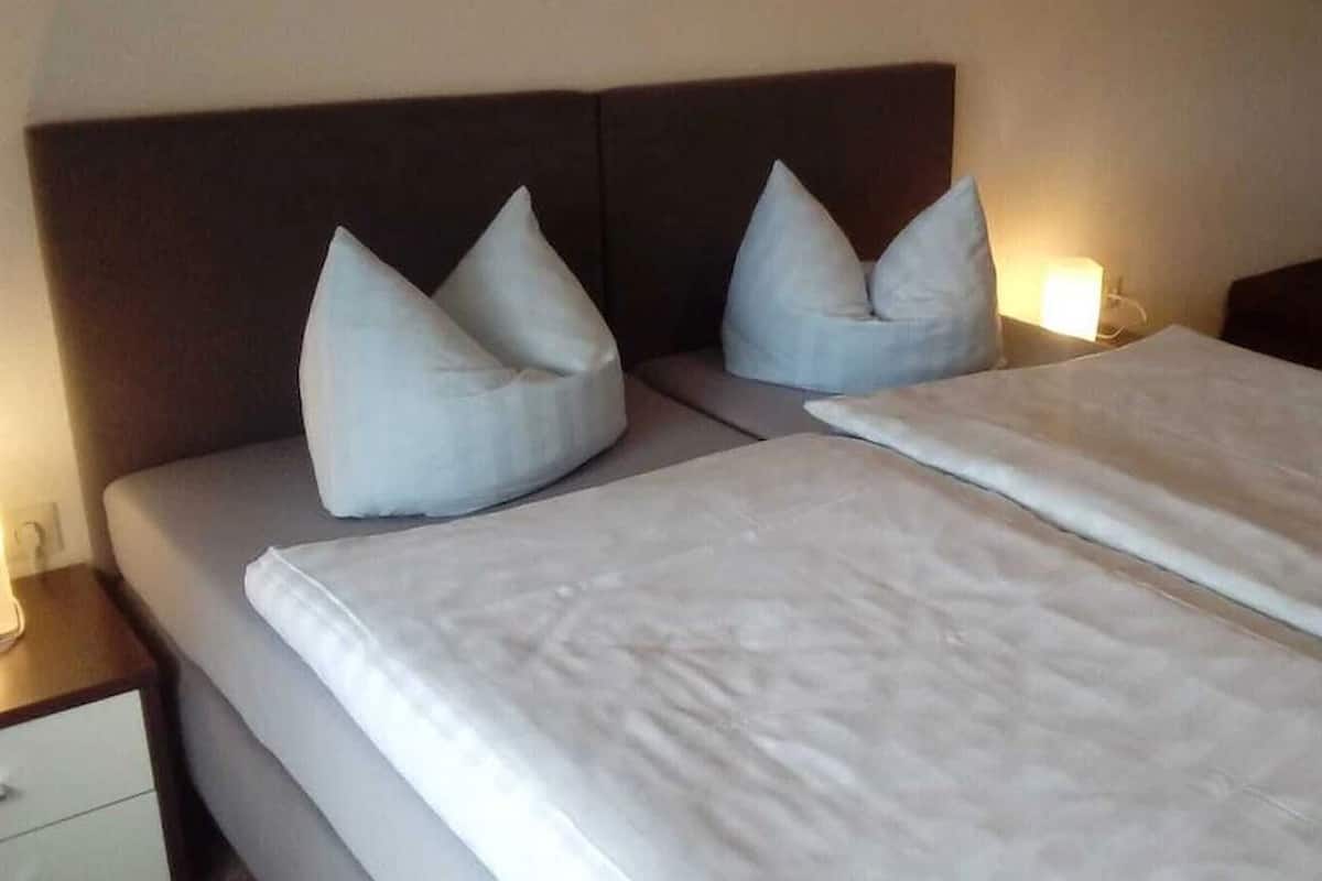 Una cama bien hecha con dos almohadas y un edredón blanco.