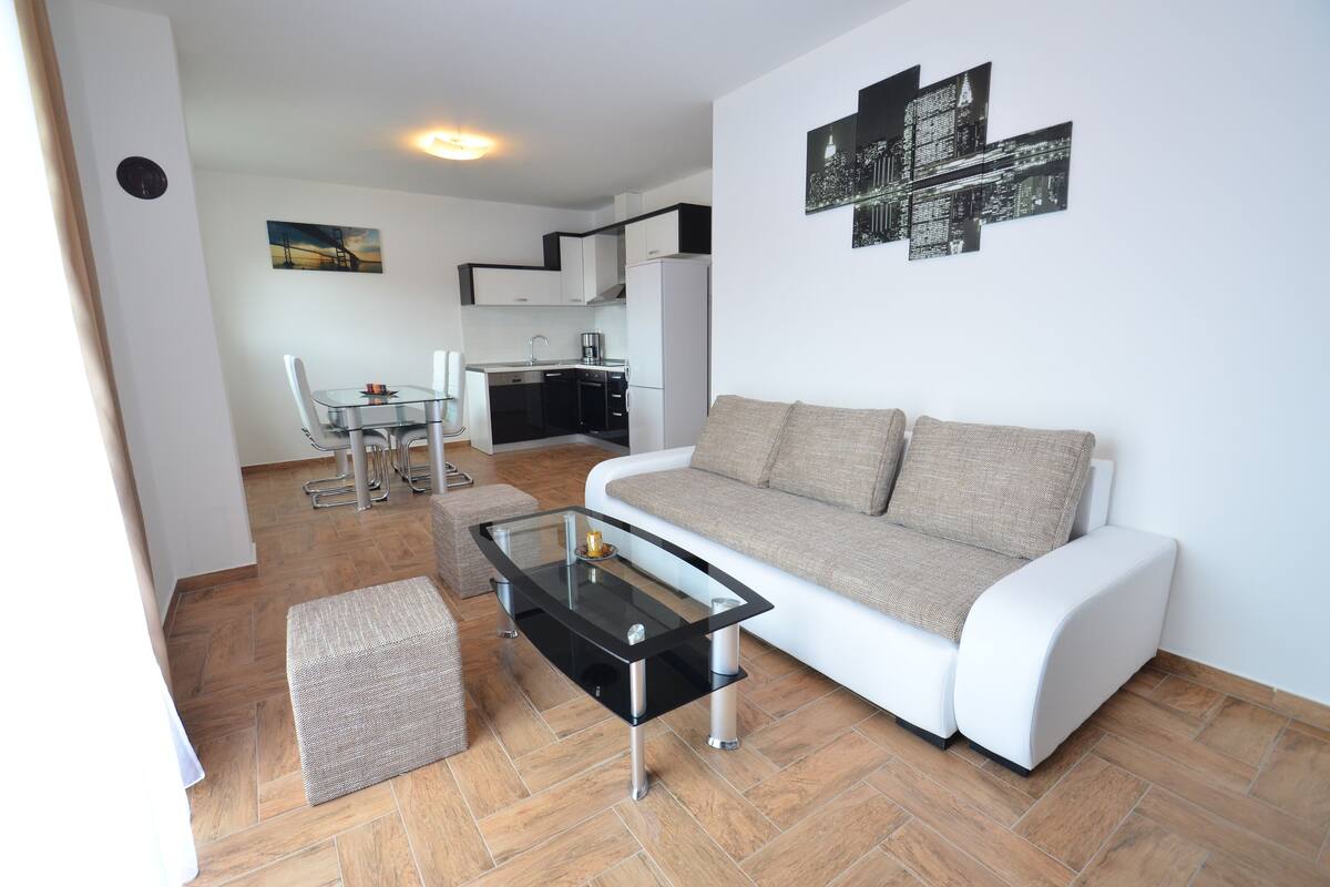Un salon moderne avec une table basse en verre, un canapé et un coin repas comprenant une table et des chaises.