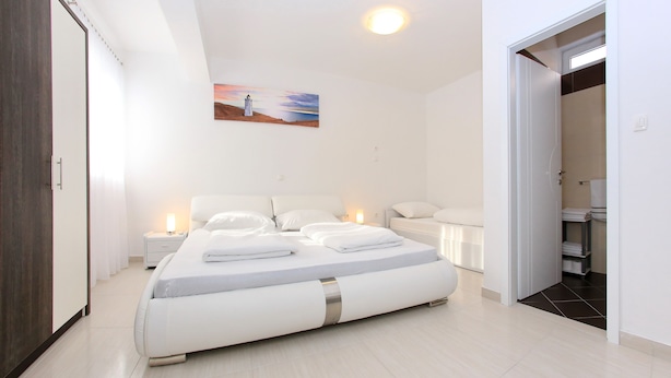 Een moderne slaapkamer met een groot bed, nachtkastjes, een nachtlampje en een schilderij aan de muur.