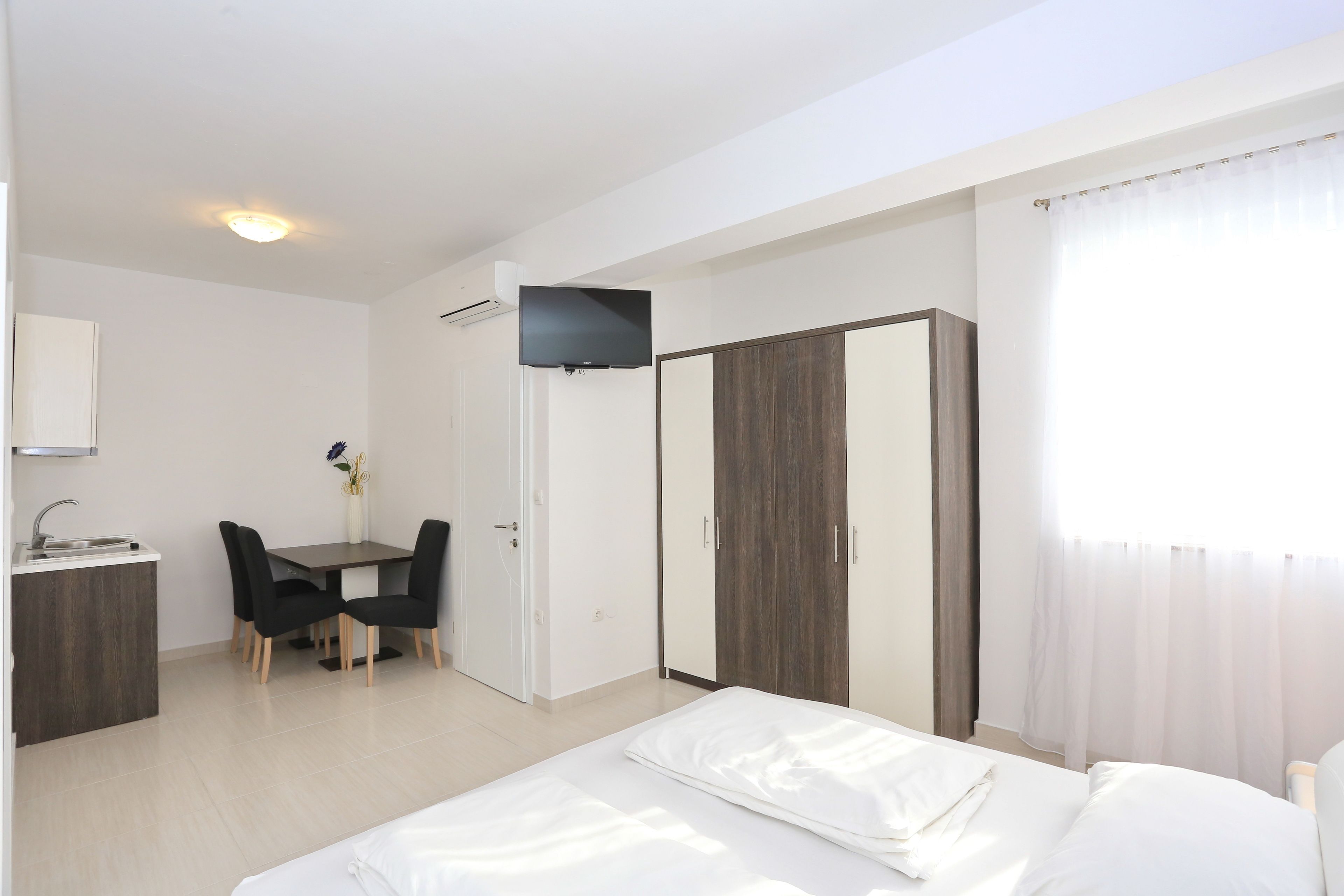 A modern hotel room with a bed, a desk, and a wardrobe.