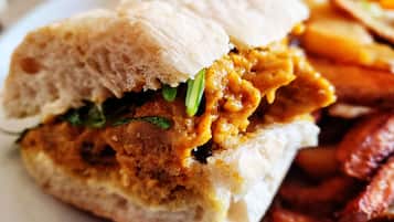 Een sandwich met een knapperige buitenkant en een vulling die lijkt op kip, geserveerd met frietjes.