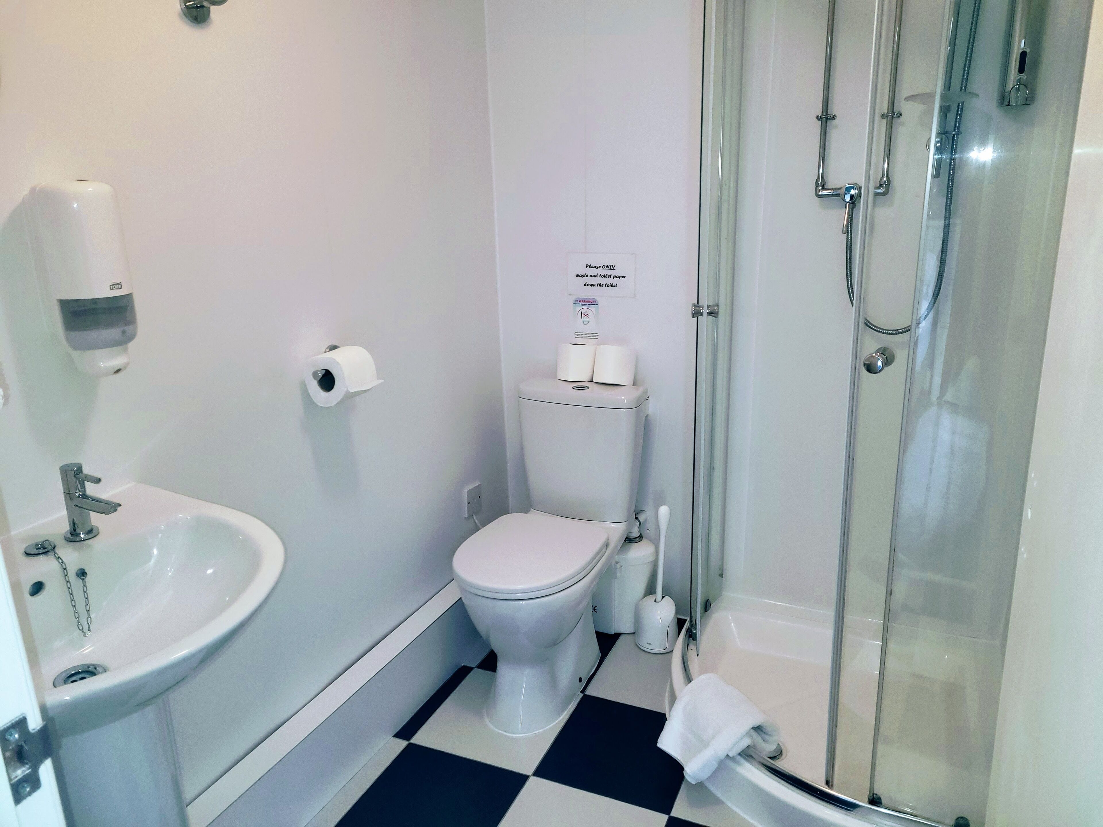 Un baño pequeño con inodoro, lavabo y ducha.