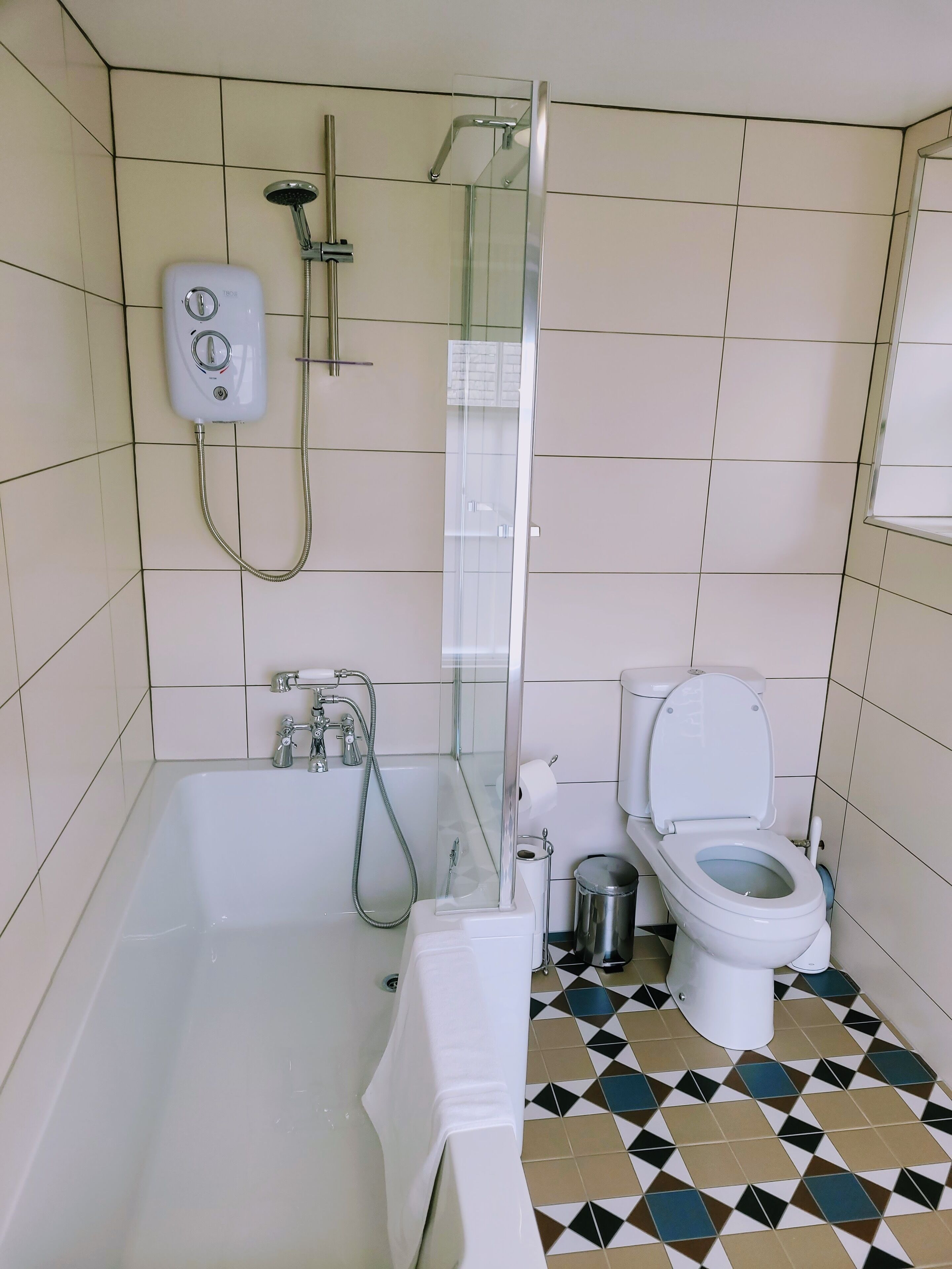 A bathroom with a bathtub, a toilet, and a glass-enclosed shower area.