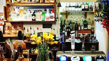 Un bar con diverse bottiglie di liquore, un rubinetto per la birra e un cartello con la scritta 'Tagerbombs £10'.