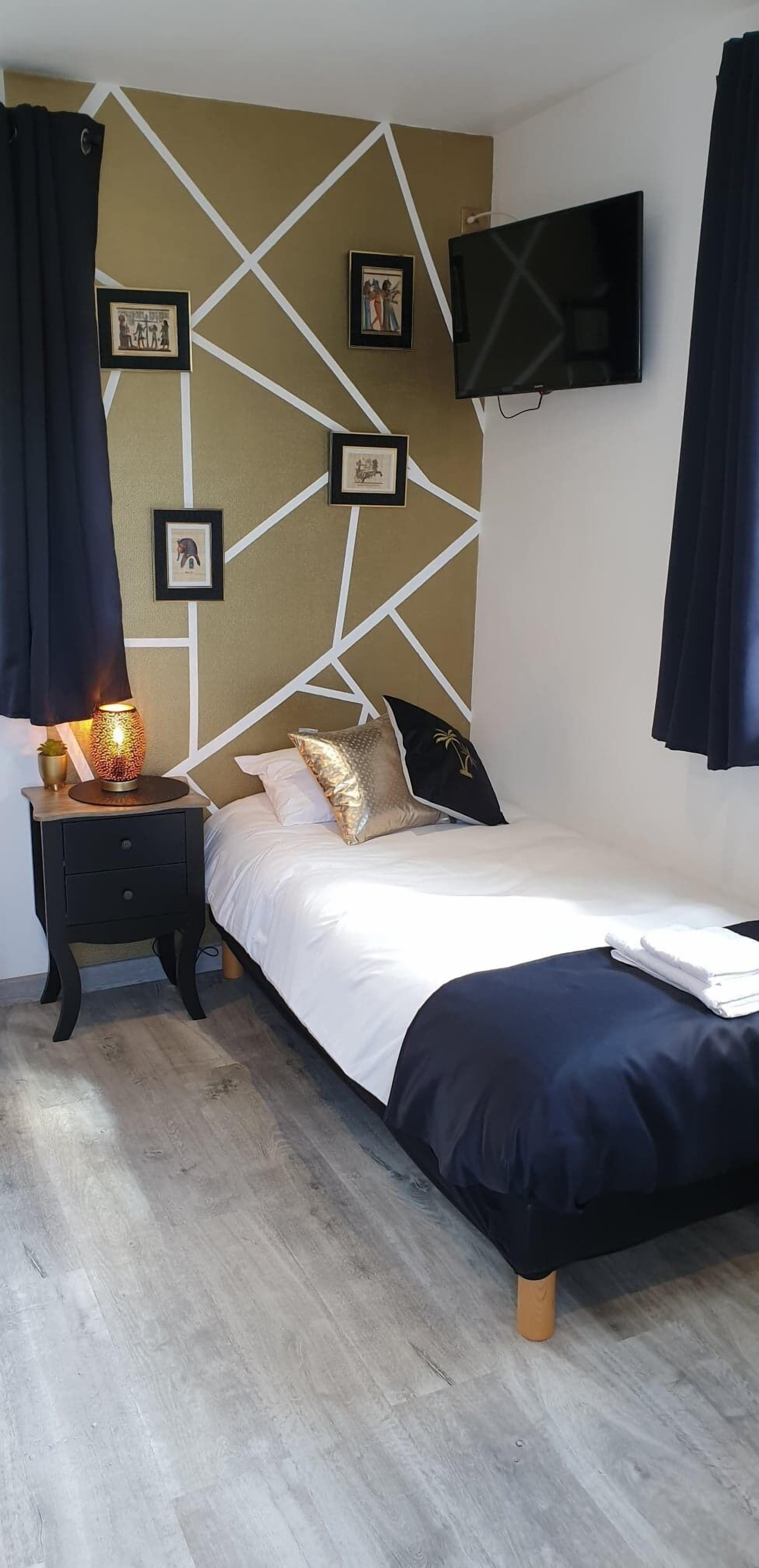 A bedroom with a bed, a nightstand, a TV, and wall-mounted pictures.