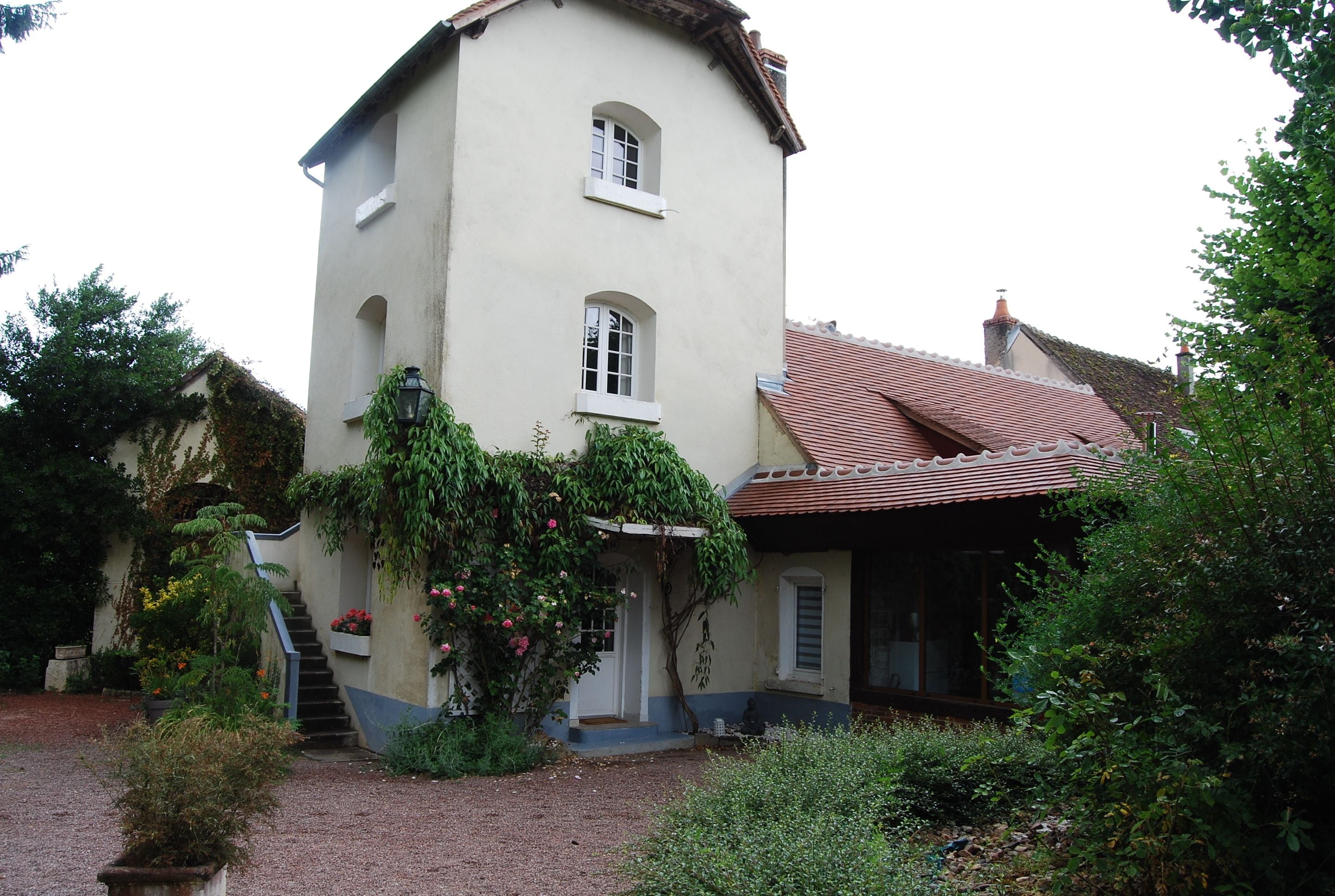 A two-story building with a sloped roof, a small porch, and a staircase leading to the entrance.