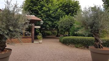 Una entrada al jardín con un edificio de ladrillo, un pérgola y un cartel que indica la entrada.