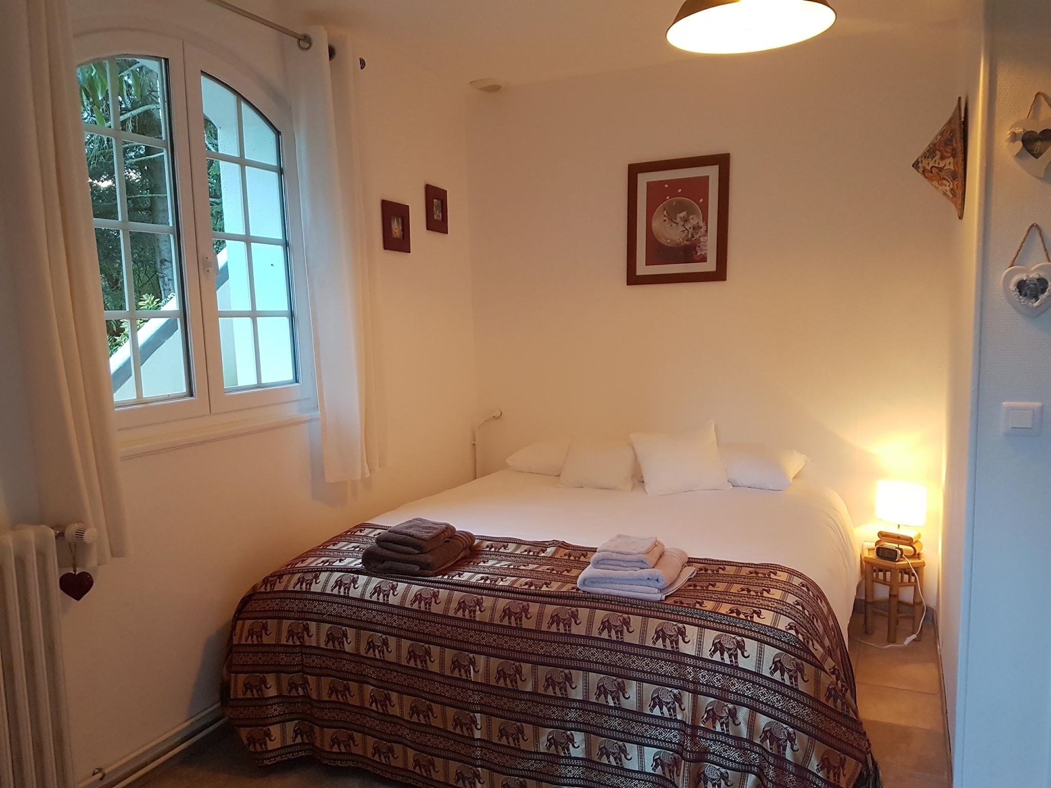 A bedroom with a large bed, a window, and a bedside table with a lamp.
