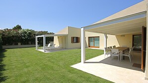 A modern house with a covered patio area, a lawn, and a dining area with outdoor furniture. - Villa Franca (San Teodoro)