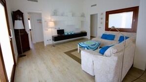 A living room with a sofa, a TV, a lamp, and a window. - Villa Franca (San Teodoro)