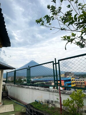 A fenced outdoor area with a view of a mountain in the distance. - Tabaco Gardenia Hotel (Tabaco City)