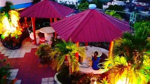A gazebo with a red roof surrounded by potted plants and a small table. - Tabaco Gardenia Hotel (Tabaco City)