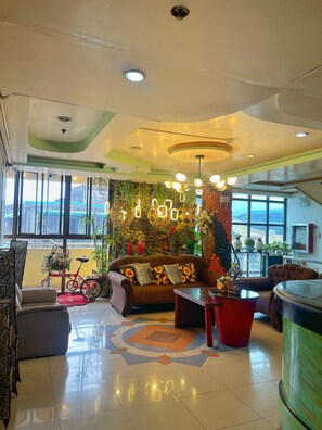 A spacious lobby with a sofa, a red bicycle, and a decorative wall. - Tabaco Gardenia Hotel (Tabaco City)
