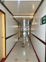 Pasillo de hotel con una señal de salida de incendios, puertas y piso de baldosas.