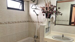 A bathroom with a bathtub, a sink, and a mirror. - Tabaco Gardenia Hotel (Tabaco City)
