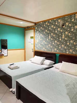 A hotel room with two single beds, a wooden headboard, a green floral wallpaper, and a small desk with a telephone. - Tabaco Gardenia Hotel (Tabaco City)