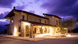 Une maison à deux étages avec une façade en pierre, un porche couvert et une entrée bien éclairée.