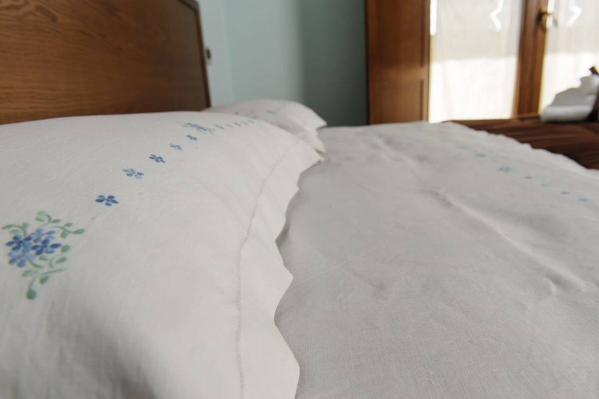 Ein ordentlich bezogenes Bett mit einer weißen Bettdecke mit blauem Blumendruck.