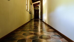 Un couloir doté d’un parquet à motifs en chevrons et de poutres en bois au plafond.