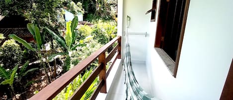 Varanda com guarda-corpo de madeira e vista para um jardim exuberante.