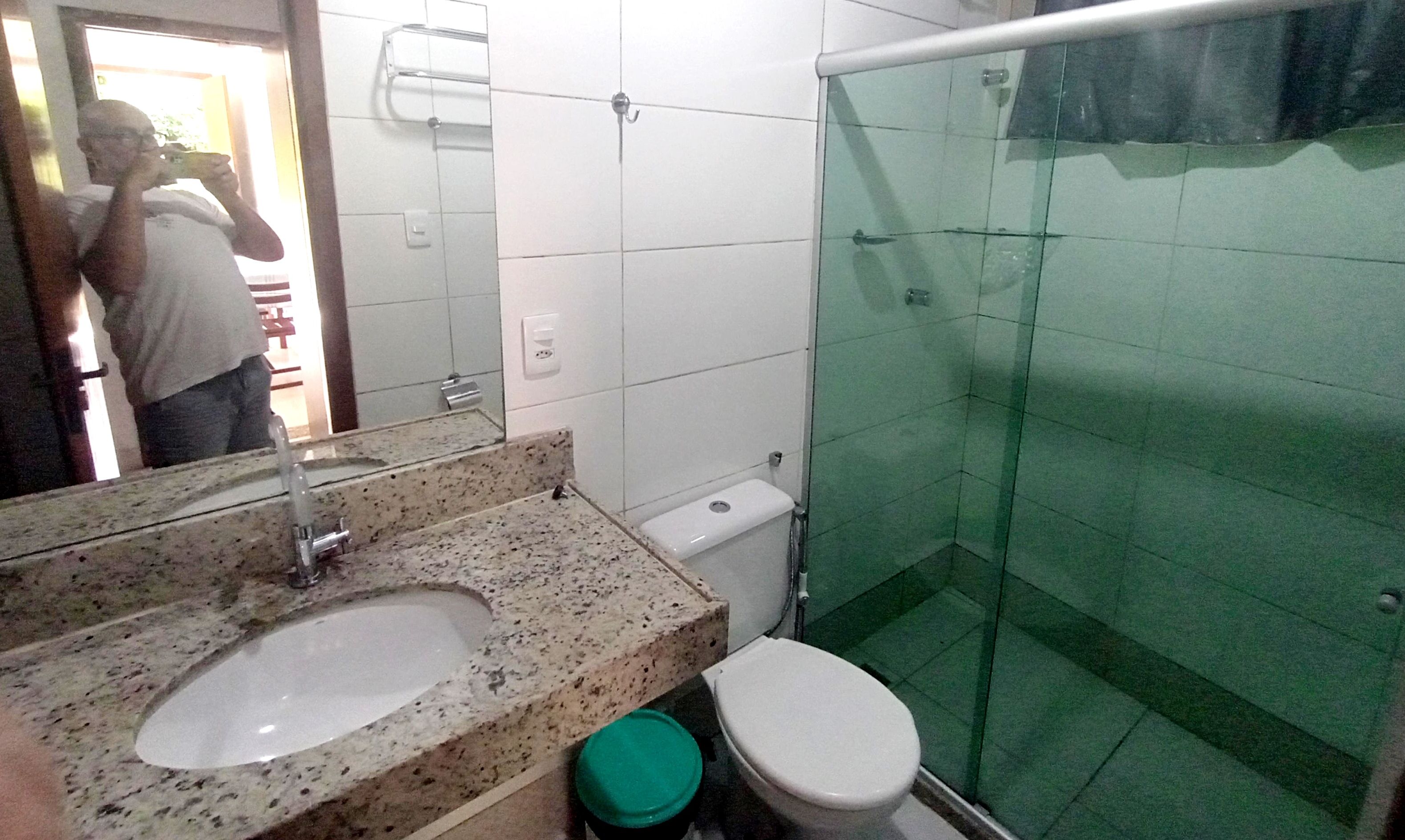 A bathroom with a double sink, a toilet, and a glass-enclosed shower.