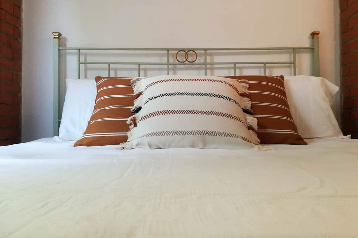 A bed with white bedding and multiple pillows, including striped and patterned designs.