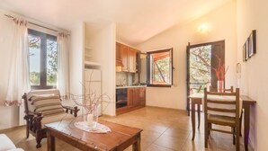 A living room with a wooden table, a sofa, and a dining area with a chair. - Villa Corallo (Pula)