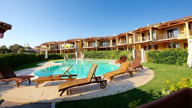 A hotel with a swimming pool surrounded by lounge chairs and a well-maintained garden. - Myrsine 2 (Olbia)