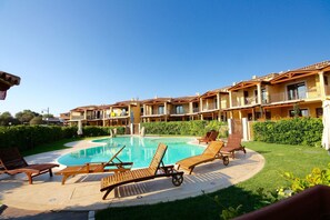A hotel with a swimming pool surrounded by lounge chairs and a well-maintained garden. - Myrsine 2 (Olbia)