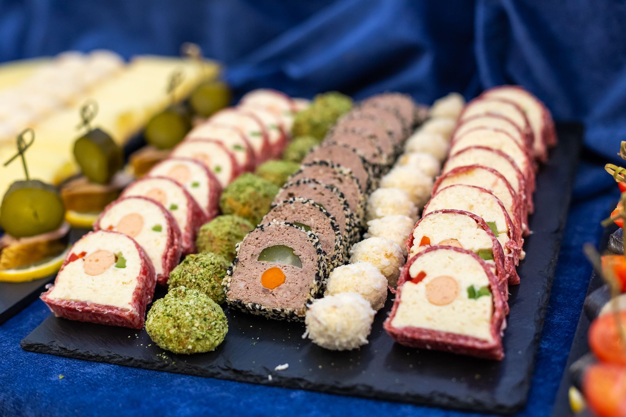 Diverse sushi rollen en andere hapjes, gerangschikt op een zwarte leisteenplank.