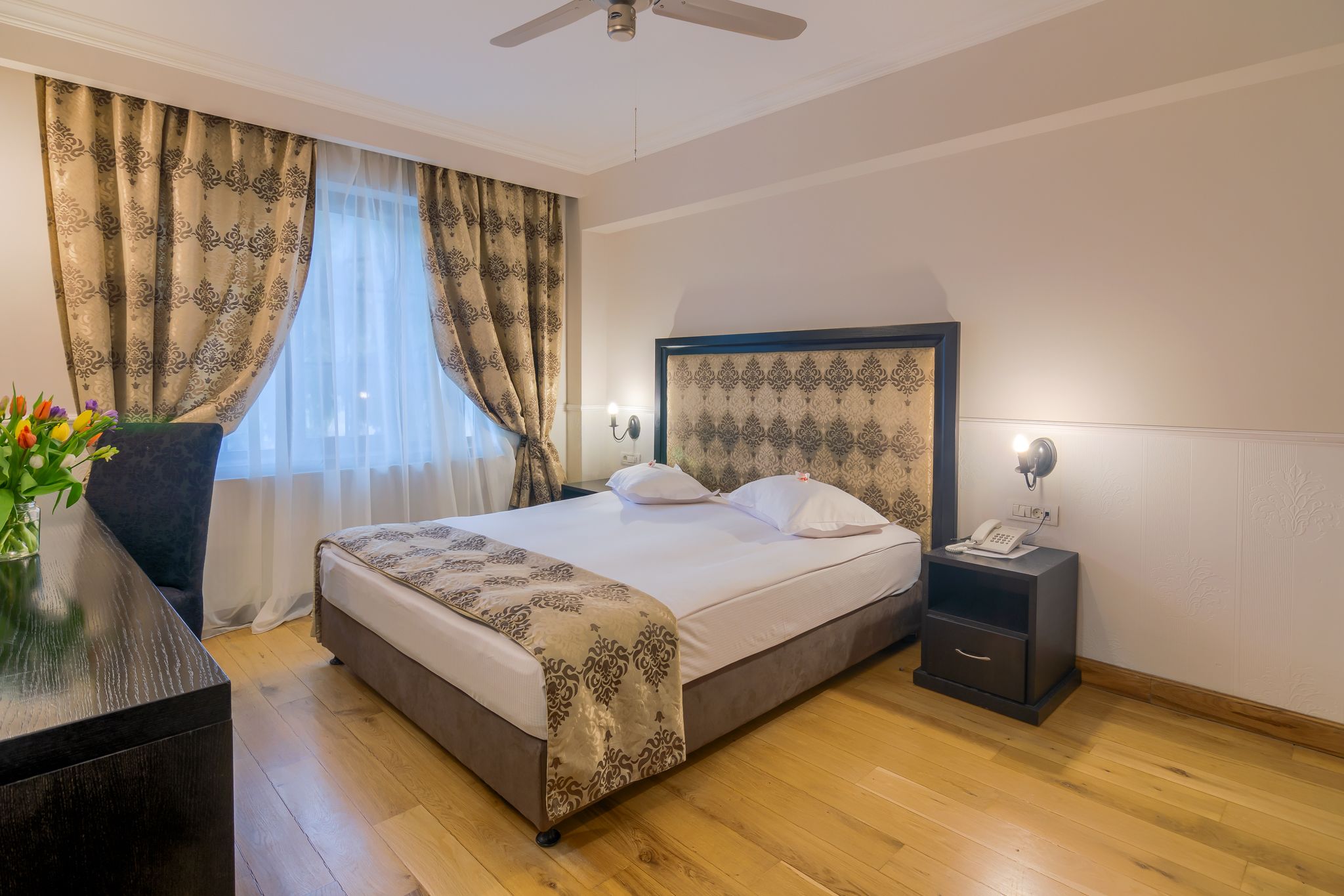 A neatly arranged hotel room with a bed, bedside table, and a nightstand with a phone.