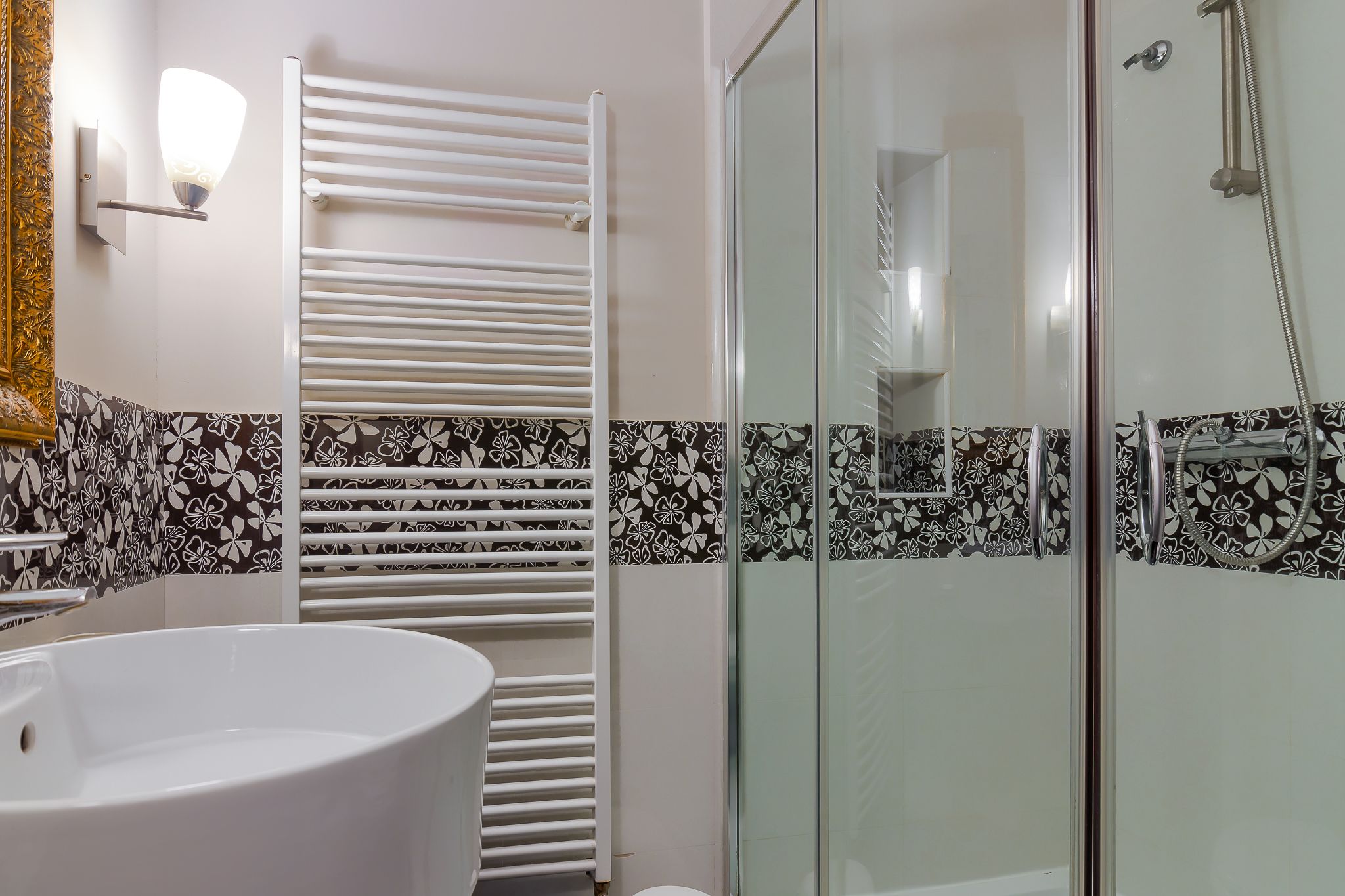 A bathroom with a white bathtub, a glass-enclosed shower, and a towel rack.