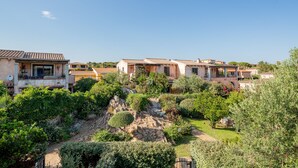 A residential area with houses featuring terracotta roofs and balconies, surrounded by lush greenery and a small stream. - Casa Anna (San Teodoro)