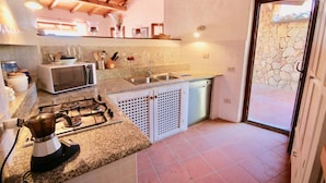 A kitchen with granite countertops, a gas stove, a microwave, and a sink. - Villa Ginepro (San Teodoro)