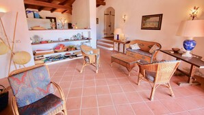 A cozy living room with wicker furniture, a tiled floor, and a wooden ceiling. - Villa Ginepro (San Teodoro)