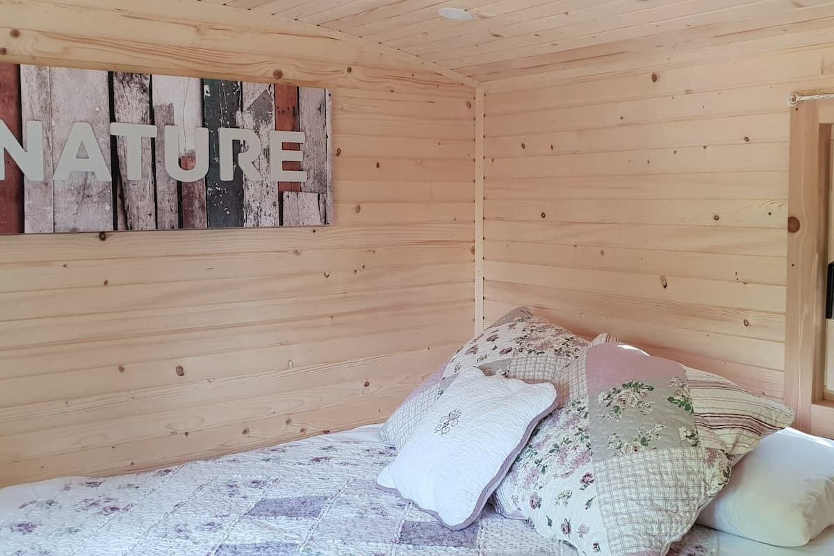 Una habitación acogedora de madera con una cama, un cartel que dice 'NATURE' y una ventana con cortinas.