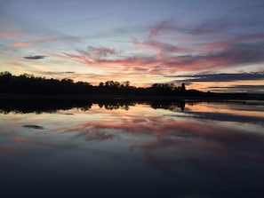 Un lago tranquilo reflejando un cielo de atardecer con nubes.