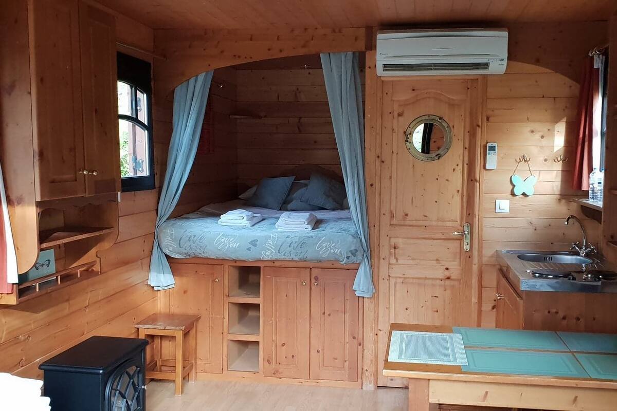 Una cabaña de madera pequeña con cama, kitchenette y ventana.