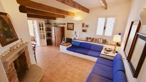 A cozy living room with a stone fireplace, a blue sofa, and a bookshelf filled with books. - Villa Beatrice (Olbia)