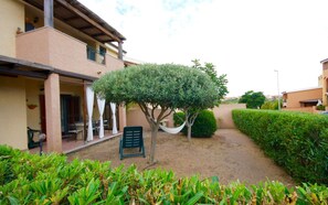 A building with a covered patio, a tree, and a chair. - Casa Antonella (Olbia)