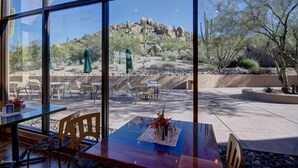 Un restaurant doté d’une terrasse offrant une vue sur un paysage rocheux parsemé de cactus et d’arbres.